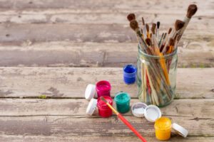 Paint brushes with gouache in bucket isolated on wooden background.Gouache paints, brush. Back to school. Creative ,Paintings art concept. hobby.Paint cans